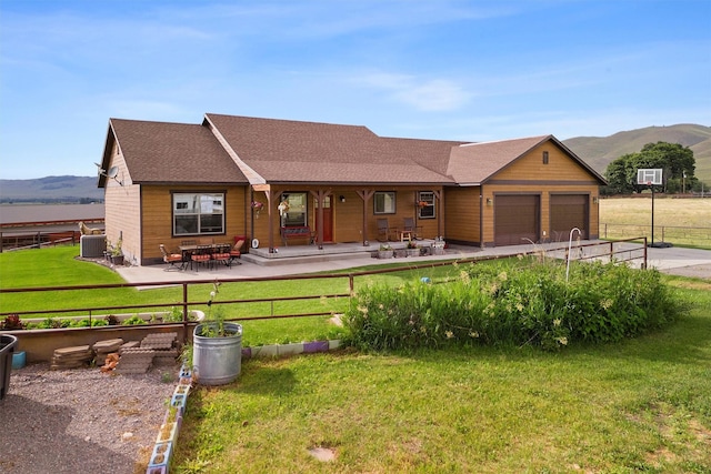 ranch-style house featuring a garage, a mountain view, central AC unit, and a front lawn