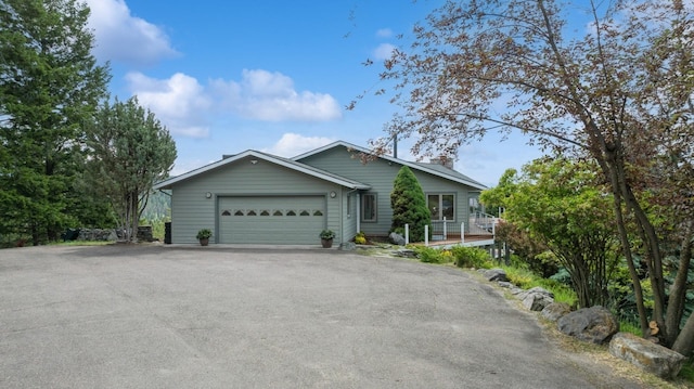 253 Pine Needle Ln, Bigfork, MT 59911 - ranch-style house featuring asphalt driveway, an attached garage, and a chimney