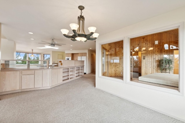 interior space featuring light carpet, ceiling fan with notable chandelier, and wooden walls