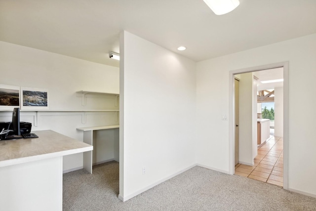 unfurnished office featuring light tile patterned floors, baseboards, and light colored carpet