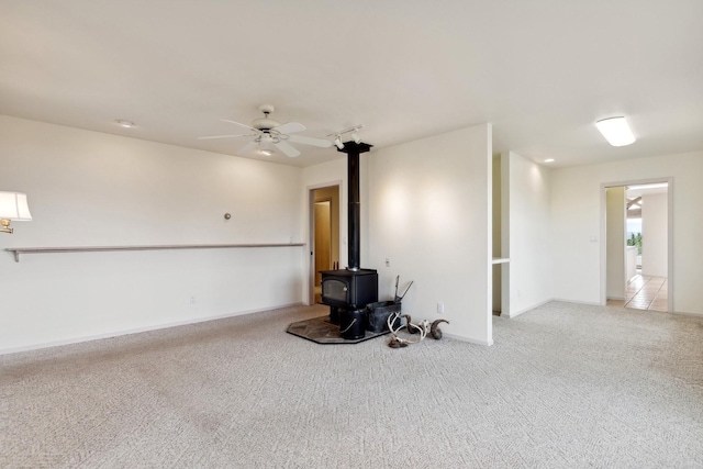 253 Pine Needle Ln, Bigfork, MT 59911 - unfurnished living room with a wood stove, carpet floors, and ceiling fan