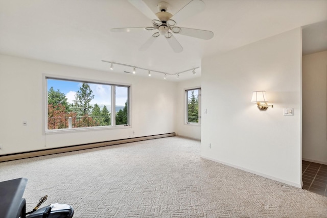 carpeted spare room featuring a baseboard heating unit, ceiling fan, baseboards, and track lighting