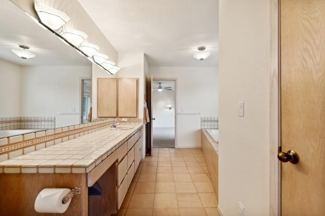 full bathroom with tile patterned flooring, tiled tub, baseboards, and vanity