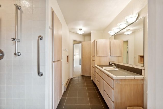 bathroom featuring vanity, a baseboard heating unit, tile patterned flooring, and a tile shower