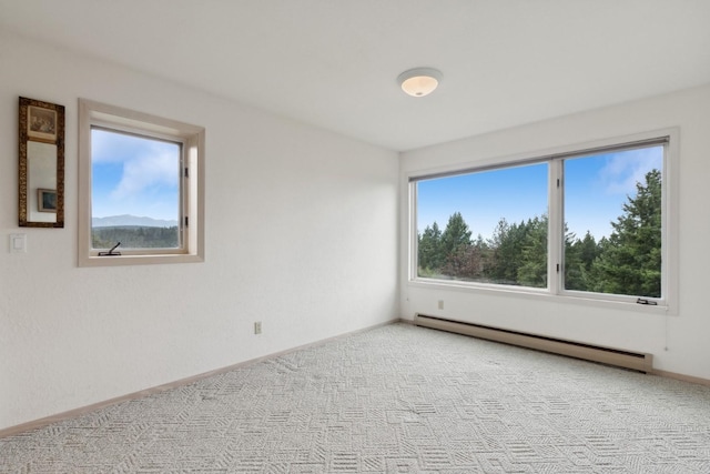 empty room with a baseboard heating unit, light carpet, and baseboards