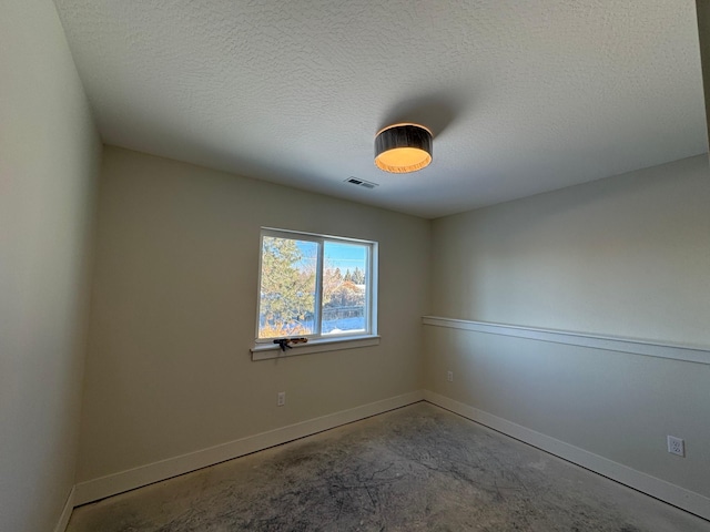 spare room featuring a textured ceiling and concrete flooring