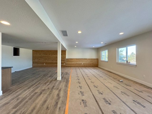 basement with a textured ceiling and wooden walls