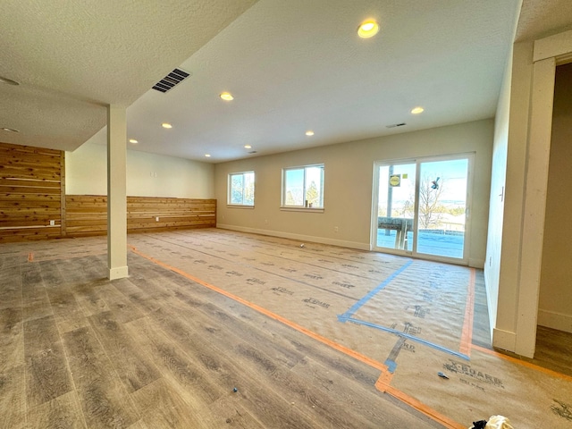 interior space featuring a textured ceiling and wood walls