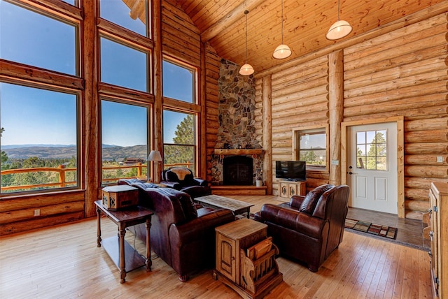 living room with a stone fireplace, wood ceiling, high vaulted ceiling, light hardwood / wood-style flooring, and log walls