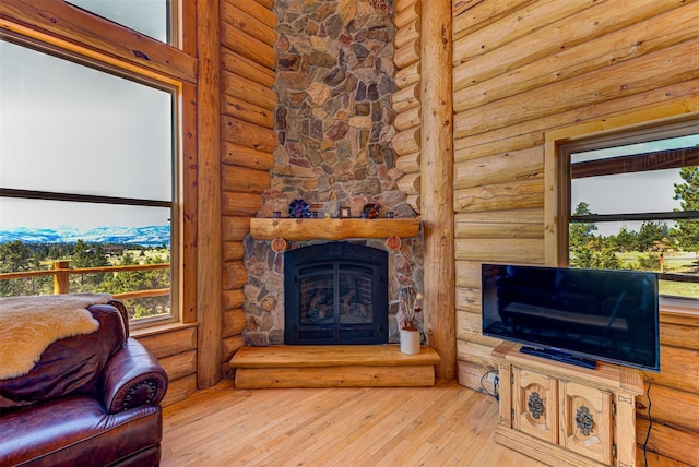 living room with a stone fireplace, log walls, and light hardwood / wood-style floors