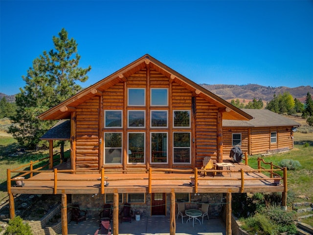 back of property featuring a deck with mountain view and a patio area