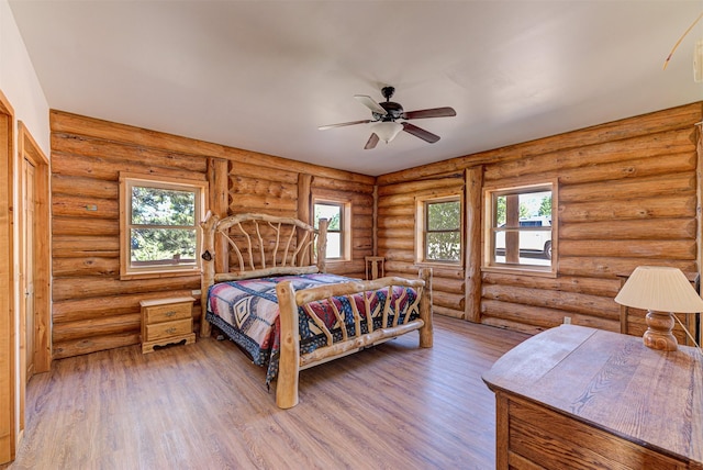 bedroom with rustic walls, hardwood / wood-style floors, and multiple windows