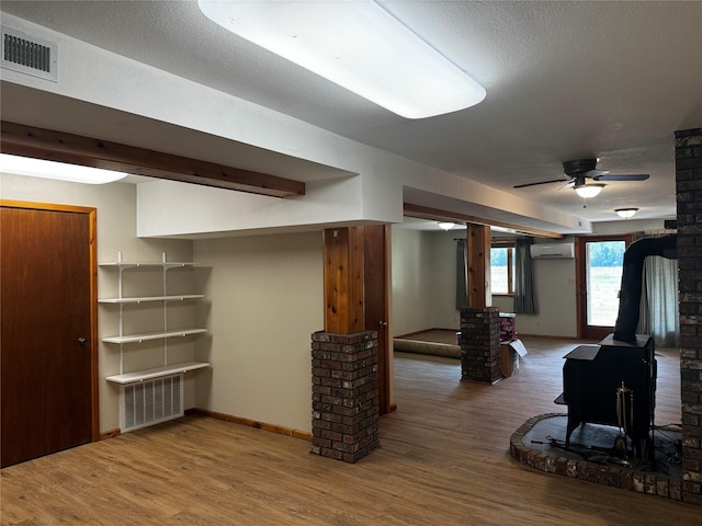 2378 Lake Creek Rd, Troy, MT 59935 - living area with a wood stove, wood finished floors, ceiling fan, a wall mounted AC, and ornate columns