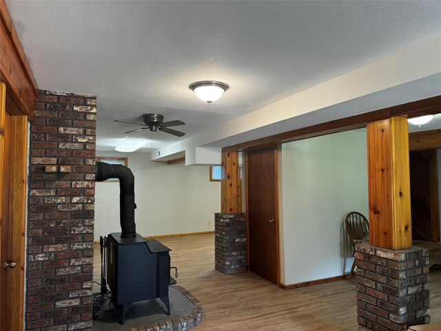 2378 Lake Creek Rd, Troy, MT 59935 - finished basement with wood finished floors, baseboards, a wood stove, a textured ceiling, and ceiling fan