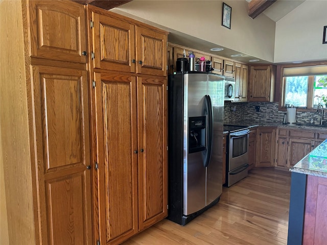 2378 Lake Creek Rd, Troy, MT 59935 - kitchen with stainless steel appliances, light wood-style floors, backsplash, brown cabinets, and beamed ceiling