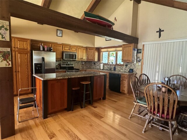 2378 Lake Creek Rd, Troy, MT 59935 - kitchen featuring stainless steel appliances, high vaulted ceiling, a kitchen island, brown cabinets, and light wood-style floors