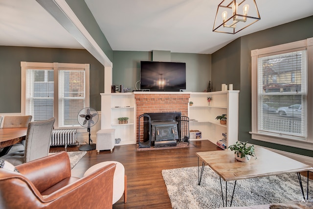 living room featuring an inviting chandelier, radiator, a fireplace, and dark wood-type flooring