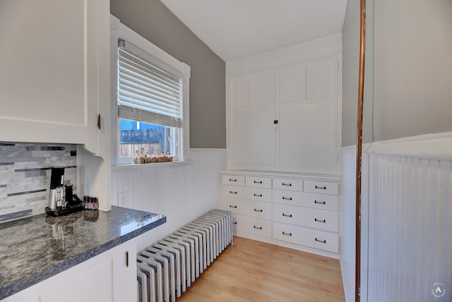 interior space featuring light hardwood / wood-style flooring, white cabinets, and radiator