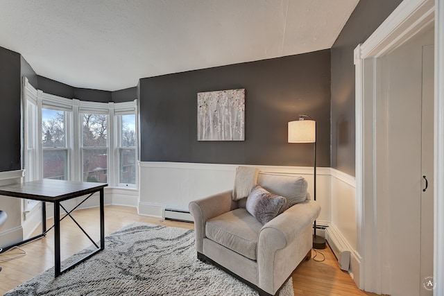 living area featuring baseboard heating and light hardwood / wood-style floors