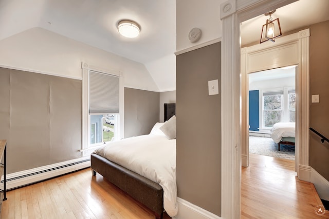 bedroom featuring lofted ceiling, multiple windows, and a baseboard radiator