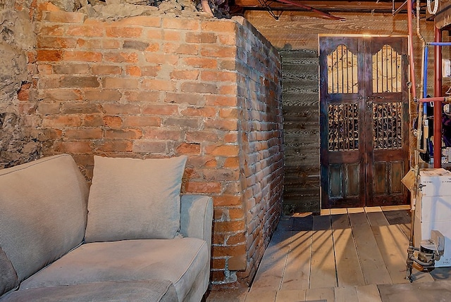 interior space with brick wall and hardwood / wood-style floors