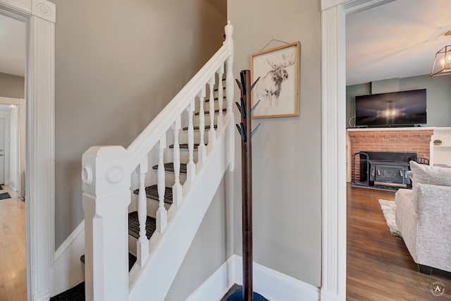 staircase featuring a notable chandelier, a fireplace, and hardwood / wood-style floors