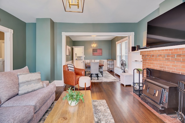 living room featuring dark wood-type flooring and a brick fireplace