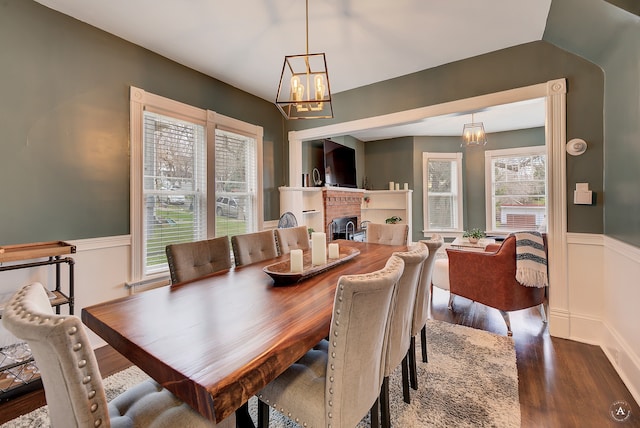 dining space featuring a notable chandelier, wood-type flooring, and a fireplace