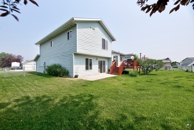 back of house featuring a wooden deck, a patio area, and a lawn