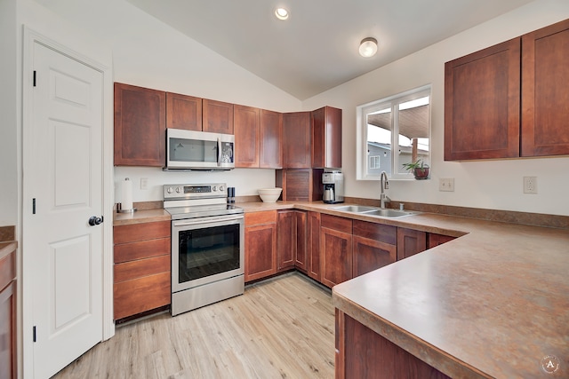 kitchen featuring vaulted ceiling, stainless steel appliances, light hardwood / wood-style floors, and sink