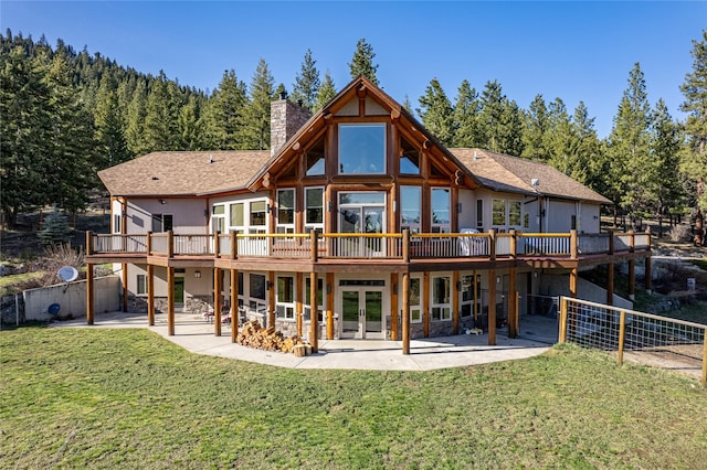 back of property featuring a wooden deck, french doors, a chimney, a yard, and a patio area