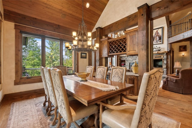 dining space featuring a chandelier, high vaulted ceiling, wooden ceiling, hardwood / wood-style flooring, and baseboards