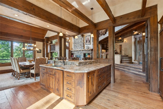 kitchen with brown cabinetry, an inviting chandelier, a sink, and light wood-style floors