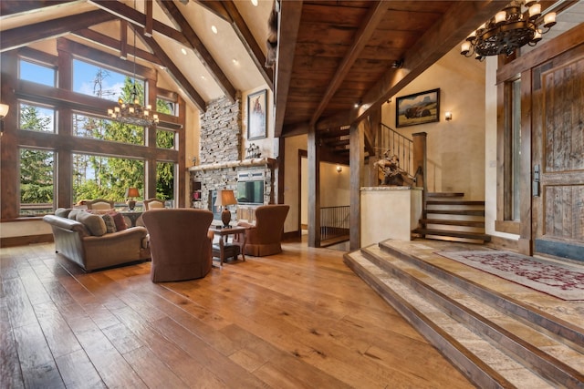 living room featuring stairway, wood-type flooring, beam ceiling, and an inviting chandelier