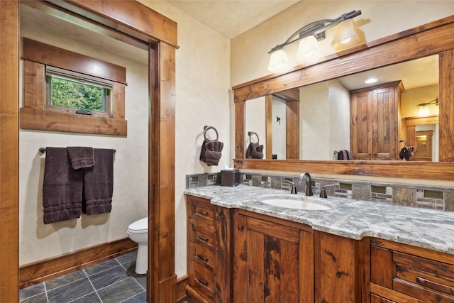 bathroom with tile patterned flooring, baseboards, vanity, and toilet