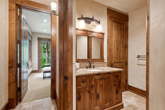 bathroom with stone finish flooring, baseboards, and vanity