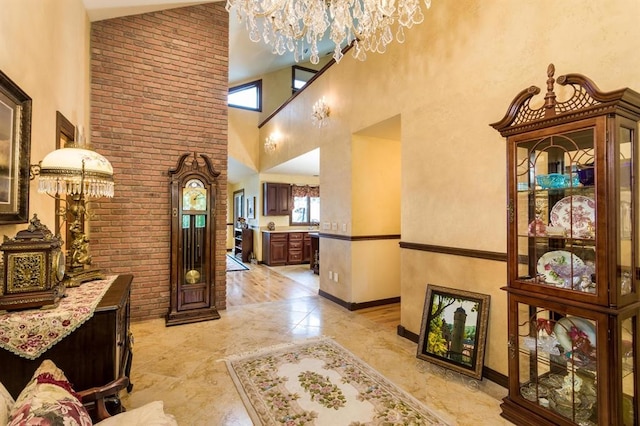 tiled foyer featuring an inviting chandelier, brick wall, a wealth of natural light, and high vaulted ceiling