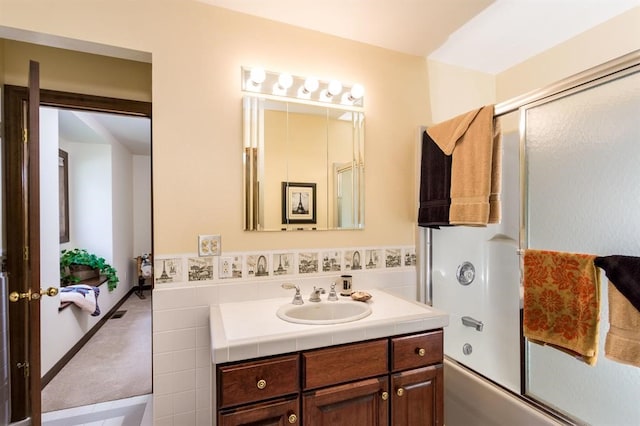 bathroom featuring combined bath / shower with glass door and vanity