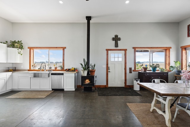 kitchen featuring dishwasher, white cabinetry, a wood stove, and a wealth of natural light