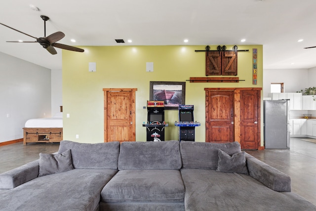 living room featuring concrete flooring, a barn door, and ceiling fan