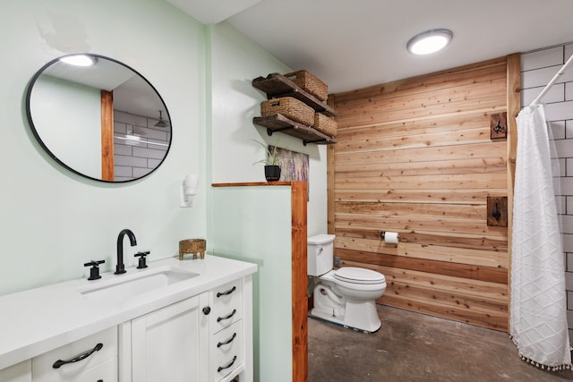 bathroom featuring vanity, toilet, wooden walls, and concrete floors