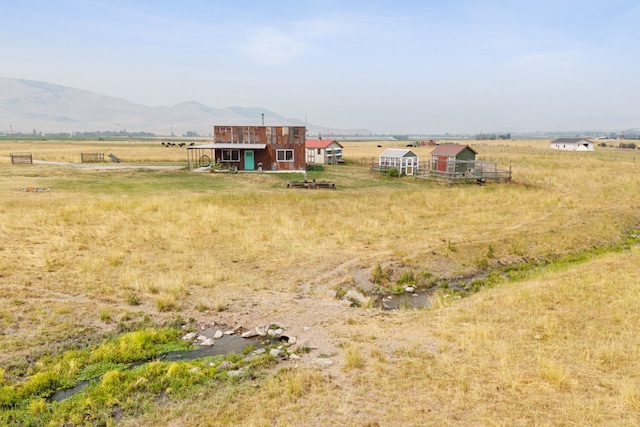 view of yard featuring a mountain view, a rural view, and an outdoor structure