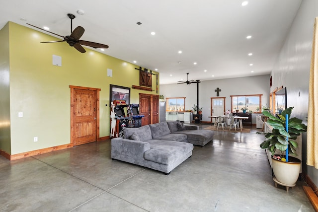 living room with ceiling fan, a high ceiling, and concrete floors