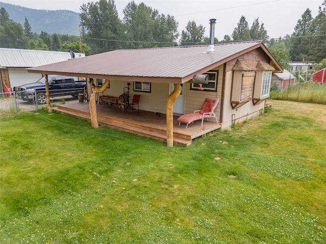 back of property featuring metal roof, fence, a deck, and a lawn