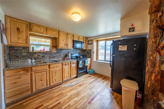 kitchen with plenty of natural light, sink, light wood-type flooring, and black appliances