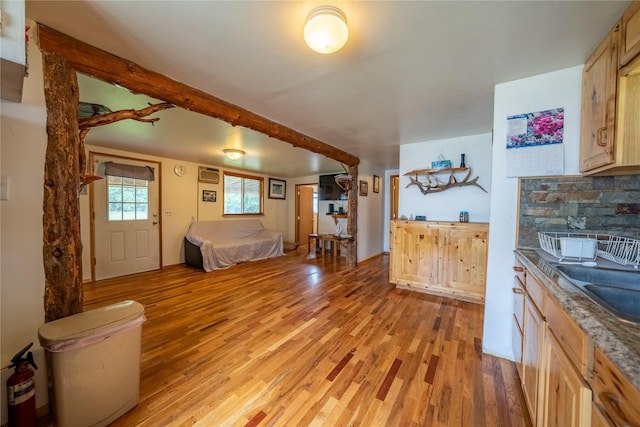 interior space with light wood-style floors, dark countertops, a sink, and light brown cabinetry