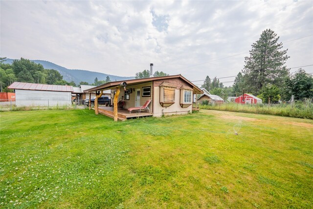 rear view of property featuring a lawn and a deck with mountain view