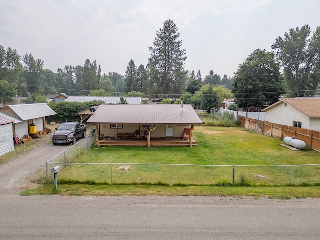 view of front facade with metal roof, driveway, a front lawn, and fence private yard