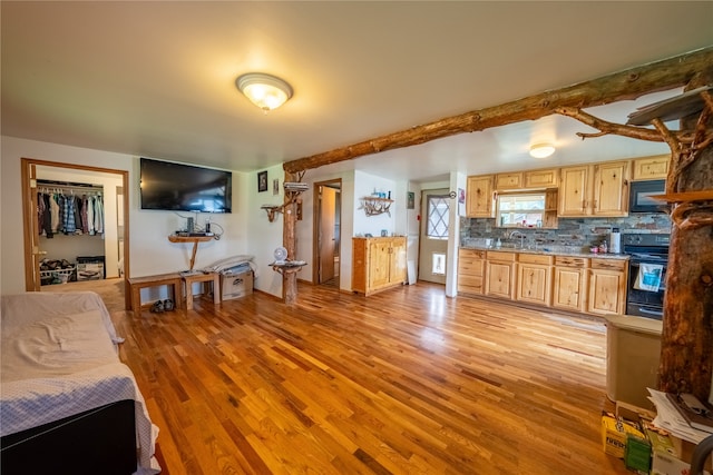 kitchen featuring sink, stove, tasteful backsplash, and light wood-type flooring