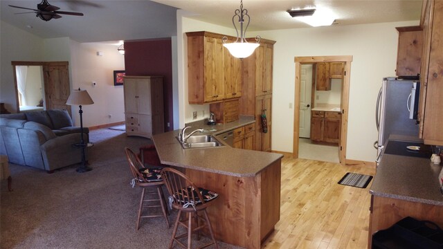 kitchen with ceiling fan, sink, decorative light fixtures, a kitchen breakfast bar, and light hardwood / wood-style floors